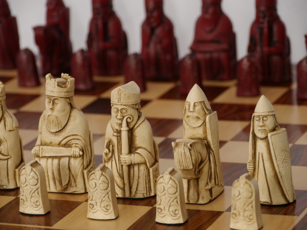 A selection of Isle of Lewis chess sets showing traditional ivory, brown and red pieces alongside aged and metal interpretations
