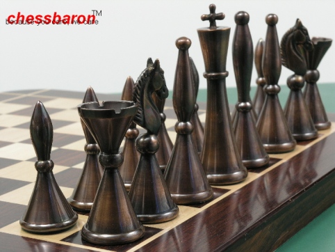 Heavy metal chess pieces in steel, copper and brass finishes displayed on a chess board
